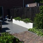 Antraciet verticale schutting, witte bloembakken, GeoCeramica gecombineerd met oud gebakken waalformaat