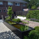 Landelijke tuin met antraciete vijver, wit grind , witte bloembakken en oud gebakken waaltjes