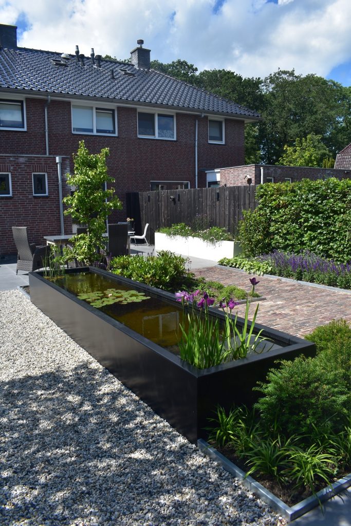 Landelijke tuin met antraciete vijver, wit grind , witte bloembakken en oud gebakken waaltjes