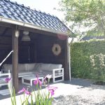 Landelijke tuin met Douglas kapschuur antraciet, wit grind, keramische tegels en dakplataan